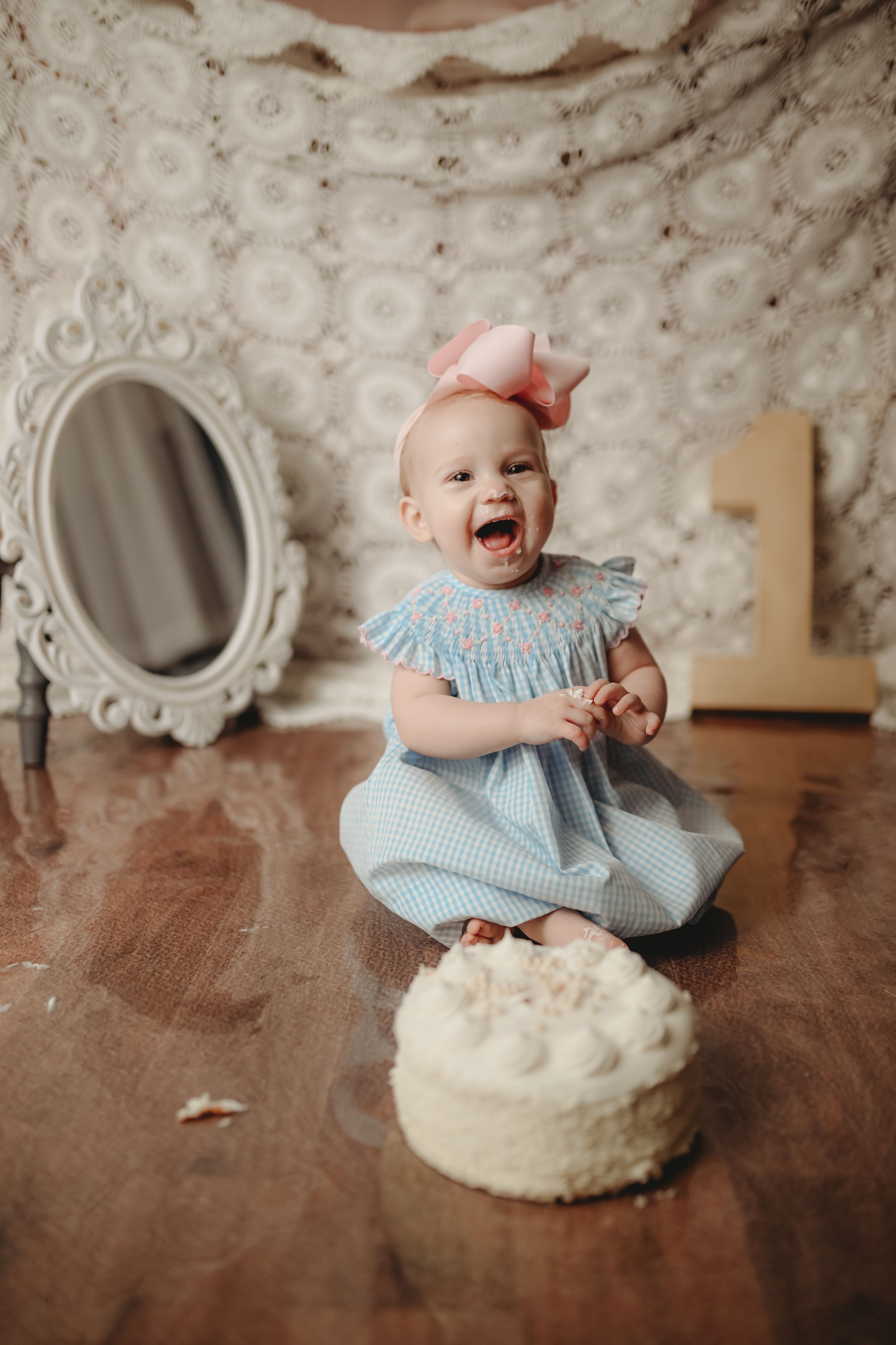 A baby in blue sits with a white cake during a first birthday cake smash photoshoot.