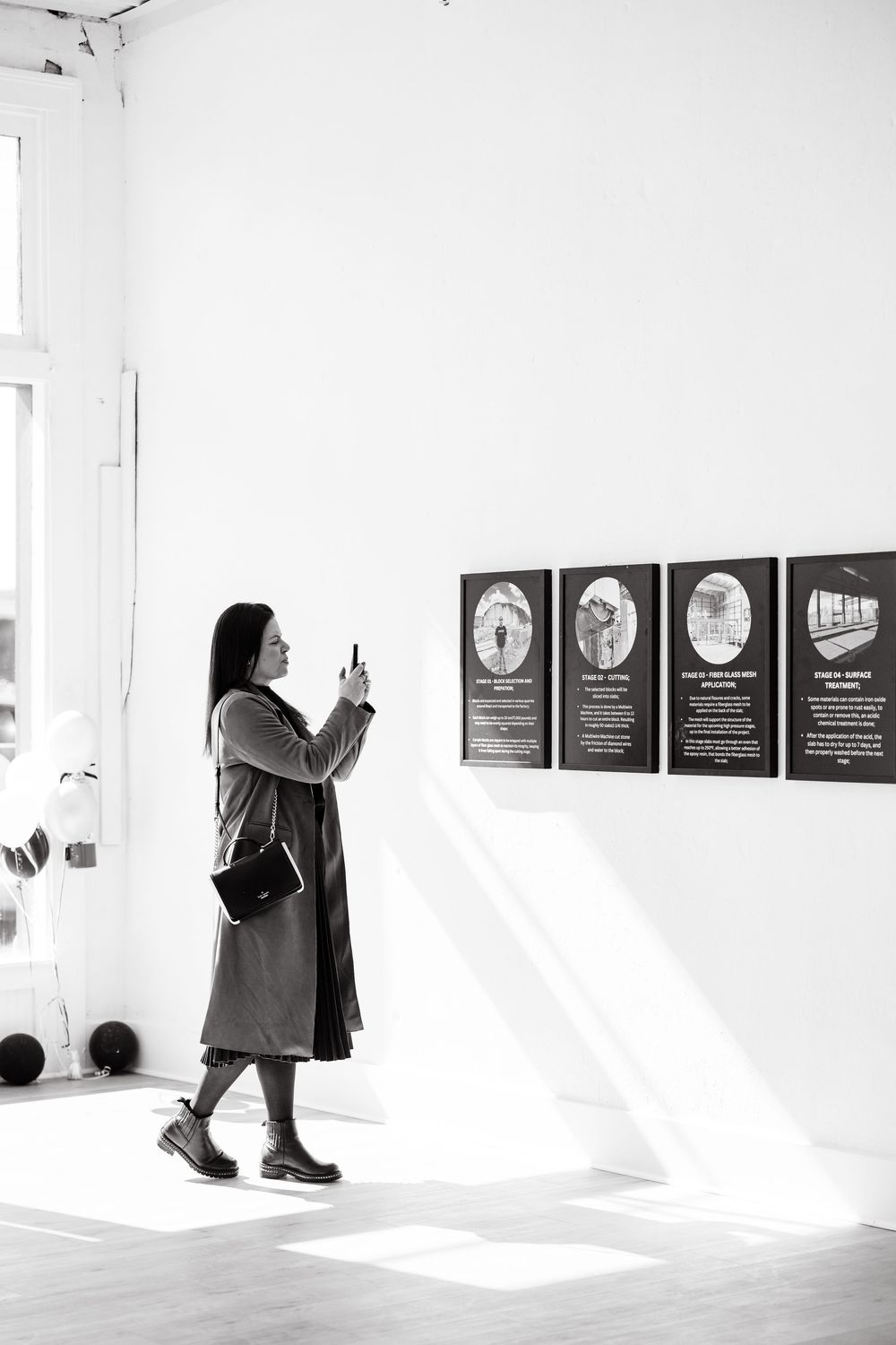Gallery visitors view framed artwork displayed in a minimalist white exhibition space.