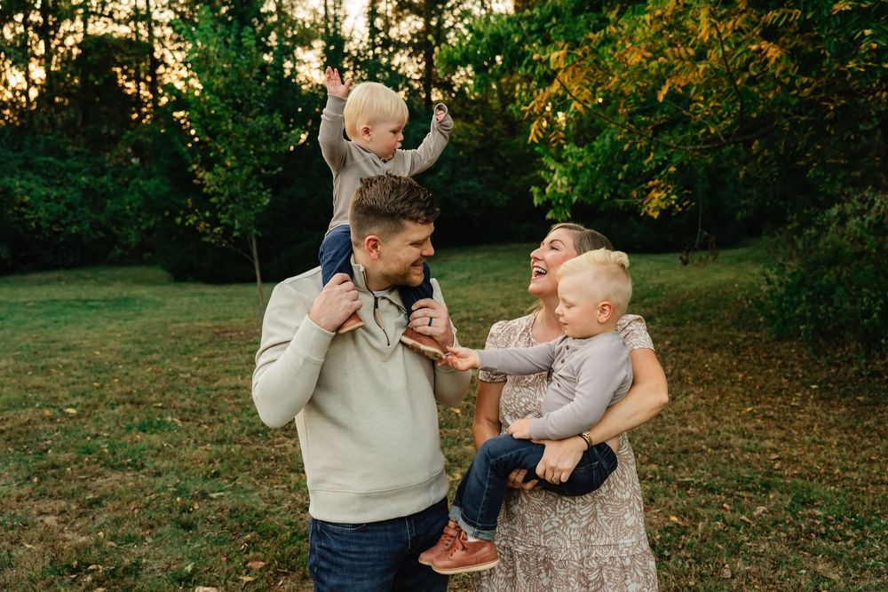 Joyful family of four playing outdoors in a lush green park during golden hour.
