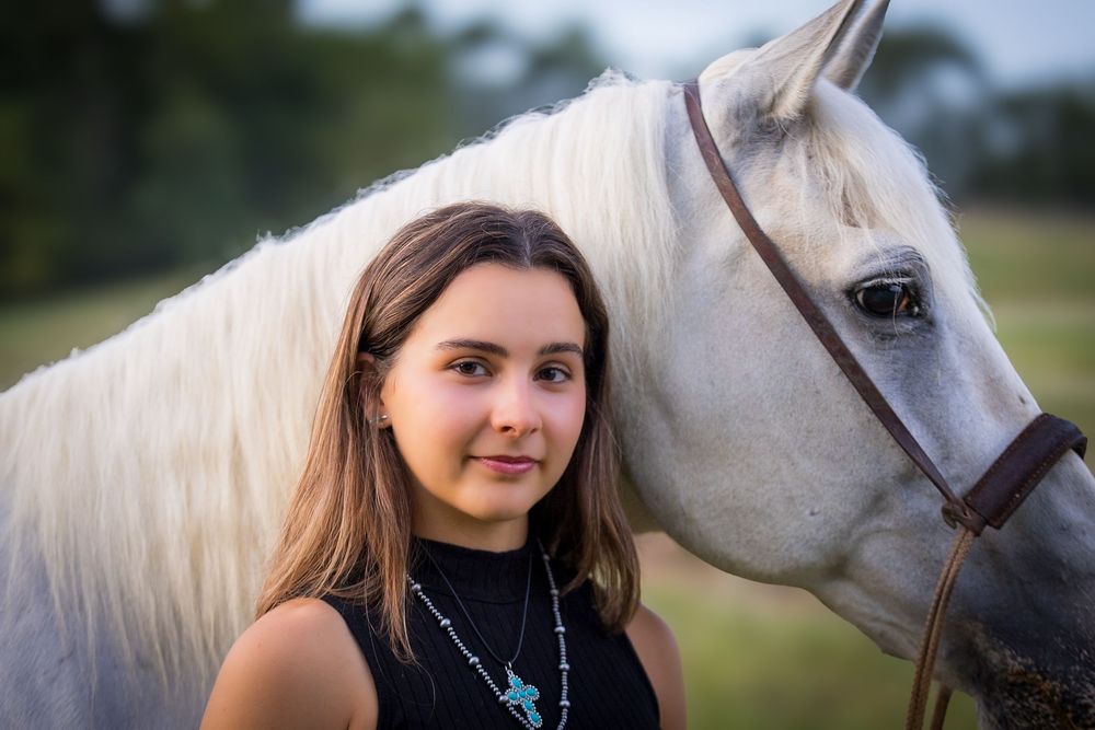 A white horse and rider share a tender moment during a photo session at sunset.