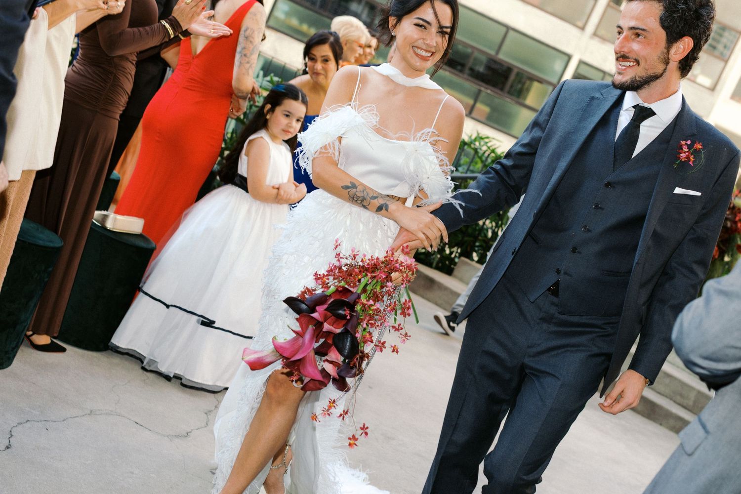 Wedding guests playfully lifting someone during outdoor celebration.