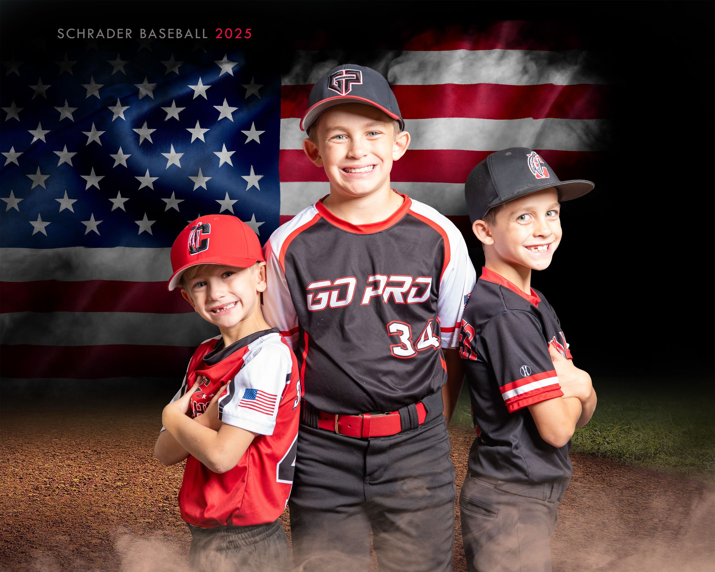 Three youth baseball players pose in front of an American flag backdrop on a baseball field.