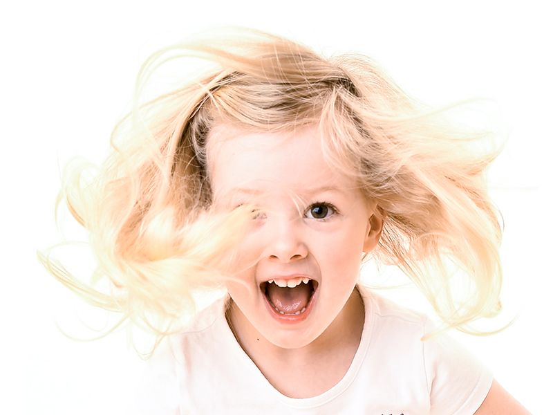 A little girl with her hair dancing in the wind and huge smile, taken by Family Photographer Abigail's Studio located in High Wycombe.