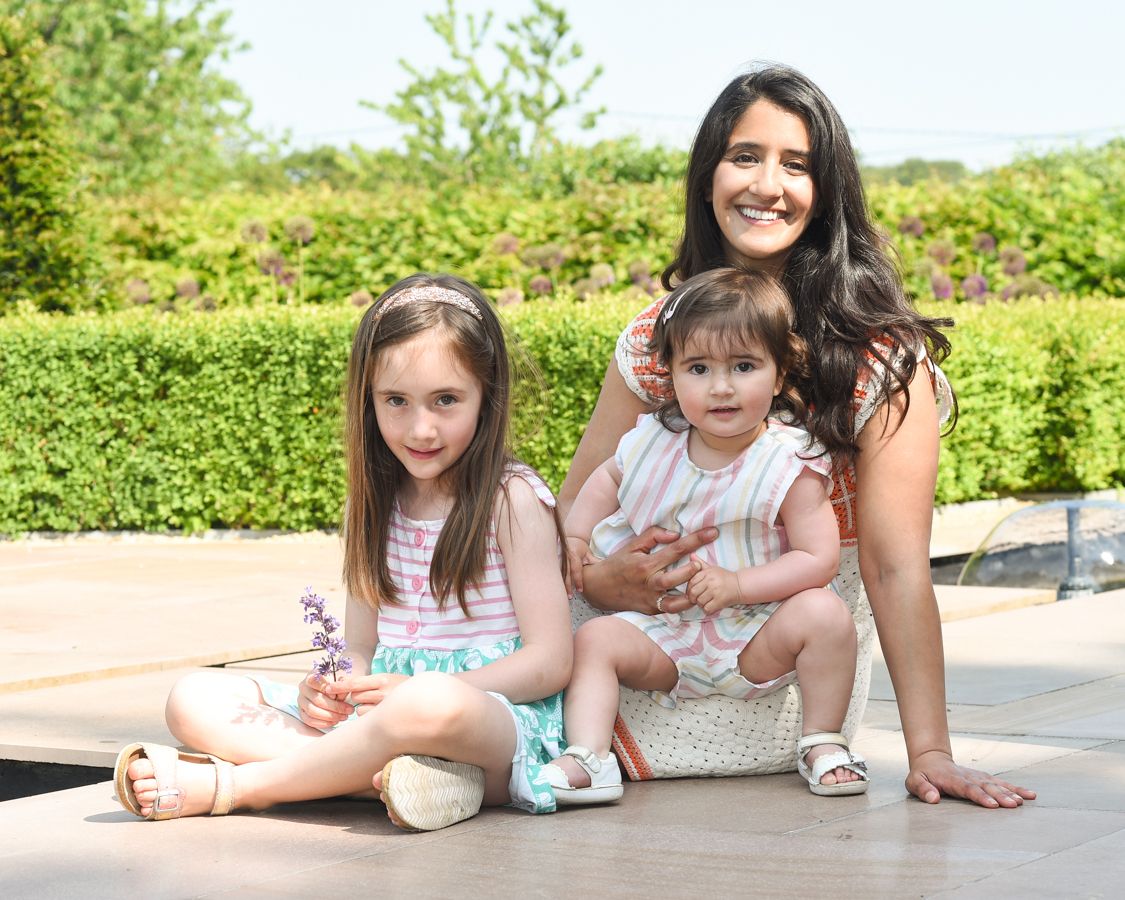 A woman and two children sit together on a stone wall, Chinnor. Photographed by Abigail's Studio.