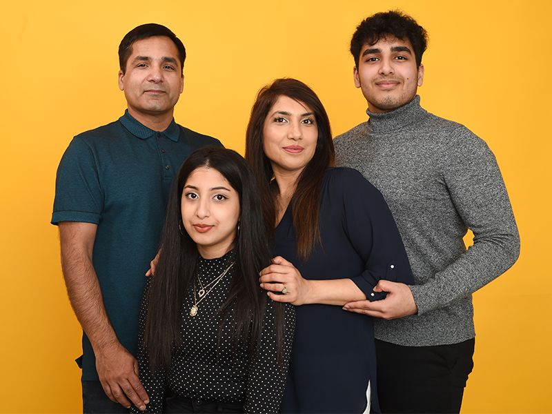 A family poses for a portrait against a vibrant yellow background, captured by Abigail's Studio Family Photographer, High Wycombe.