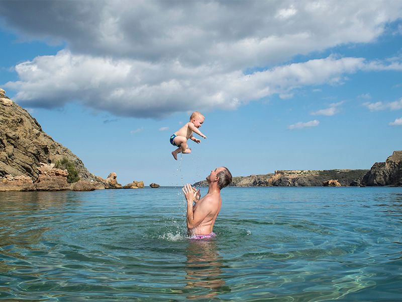 A joyful moment of a man and a baby playing in the water, photographed by Abigail's Studio, High Wycombe.