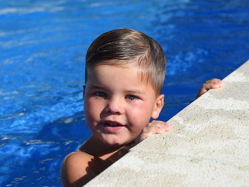A young boy plays in a swimming pool, captured during a photoshoot by Abigail's Studio in Buckinghamshire.