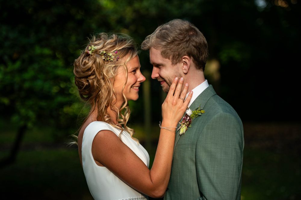 Liebespaar teilt einen intimen Moment im Freien während ihrer Hochzeit, mit üppigem Grün im Hintergrund.