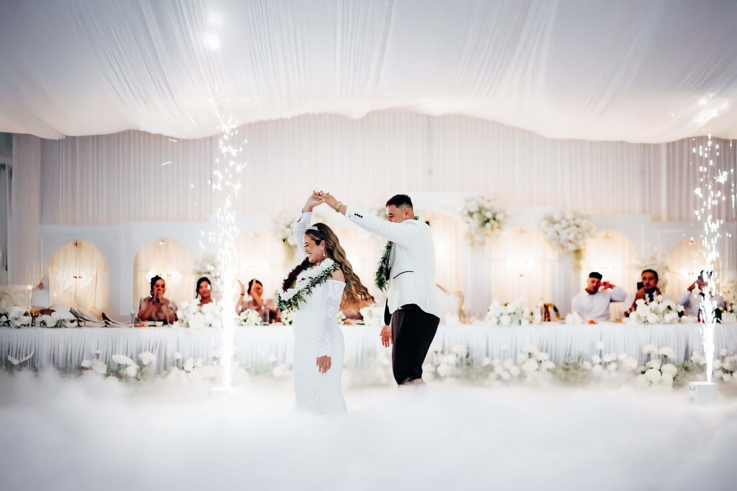 A wedding reception panorama showing a white-decorated banquet hall with guests seated at elegantly arranged tables.