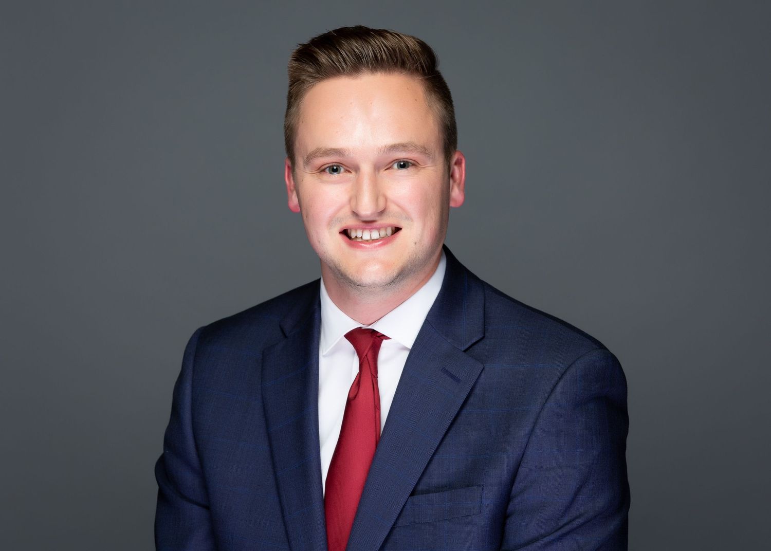 Professional headshot of a businessman smiling against a neutral gray background in Fargo, ND
