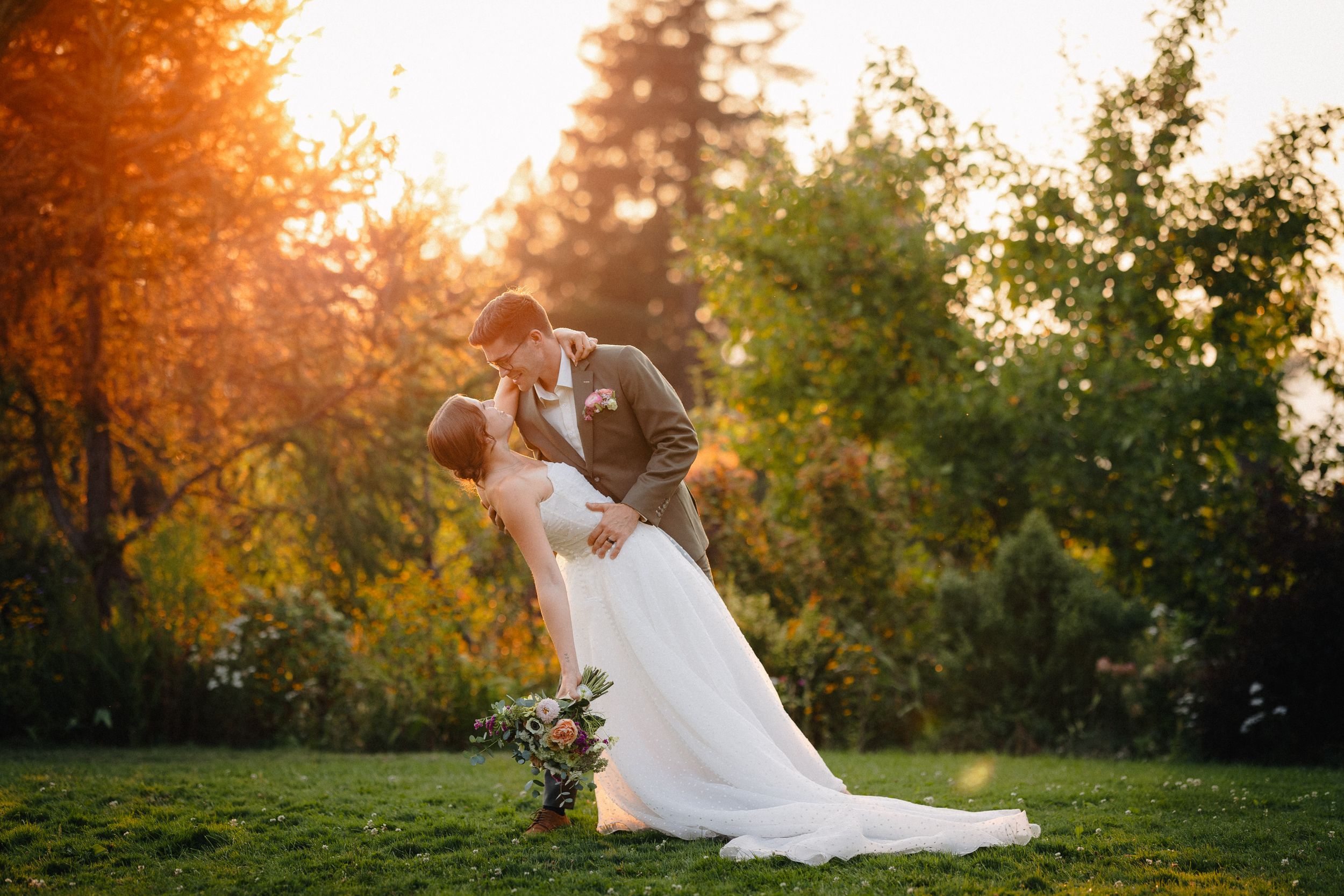 A romantic sunset garden wedding scene with a graceful dip pose and autumn foliage creating a warm golden backdrop.