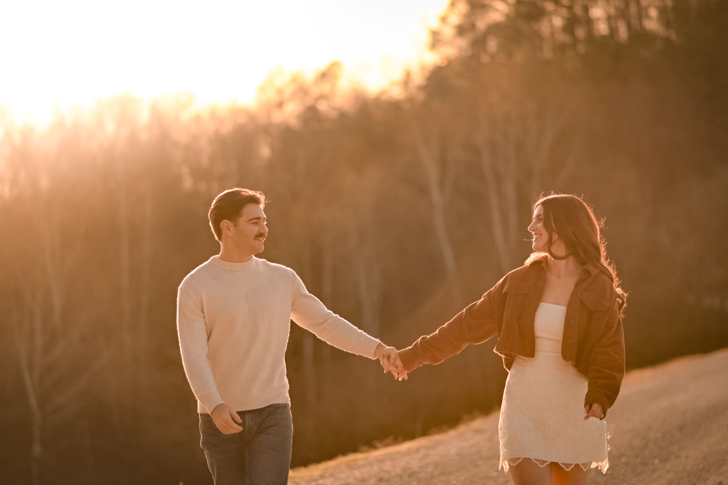 A couple dances together in warm sunset lighting outdoors.