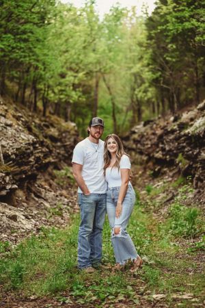 Couple poses in wooded area during outdoor photo session.