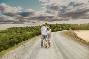 Romantic couple walking together on a winding dirt road through scenic countryside at sunset.