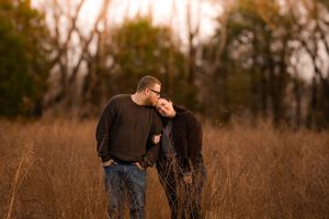 A romantic couple embracing in a golden field at sunset.