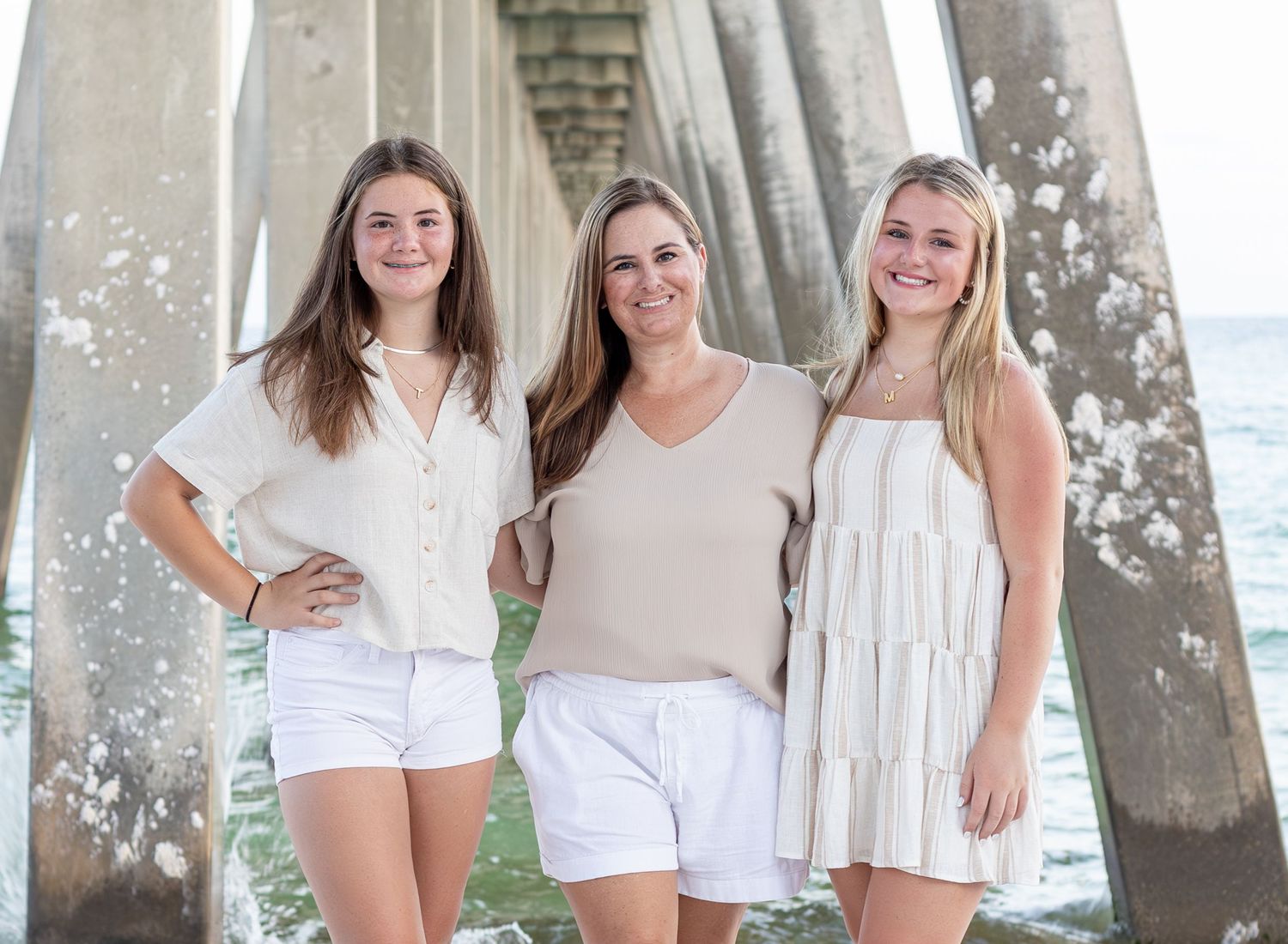 mom and two daughters on beach with pier