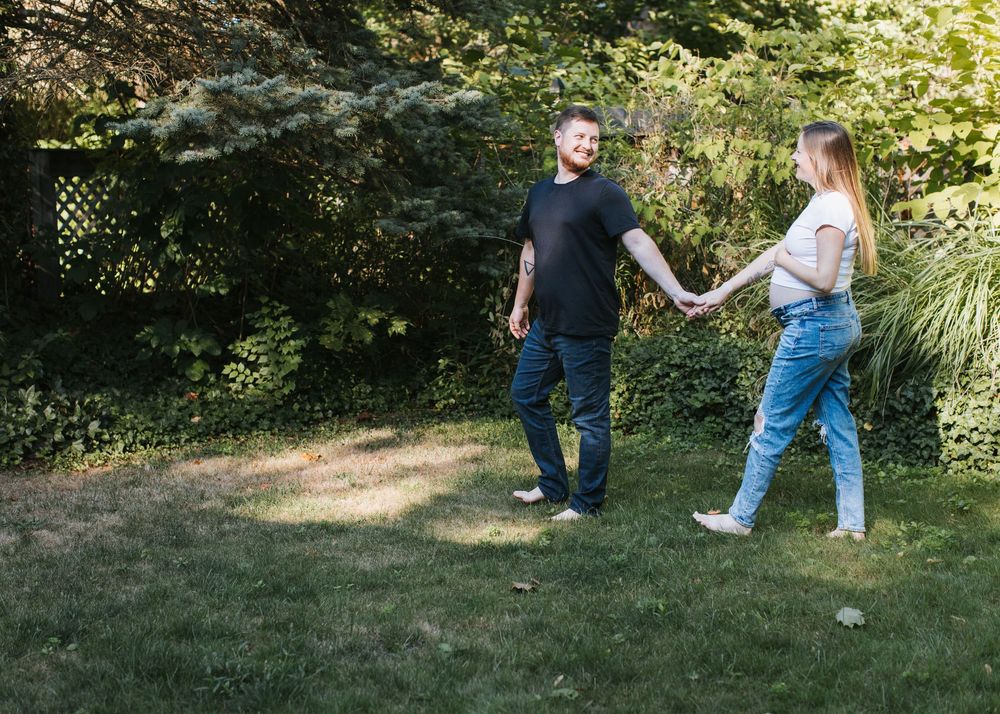 Hannah and David walking through backyard during their lifestyle maternity session in Flint, Michigan