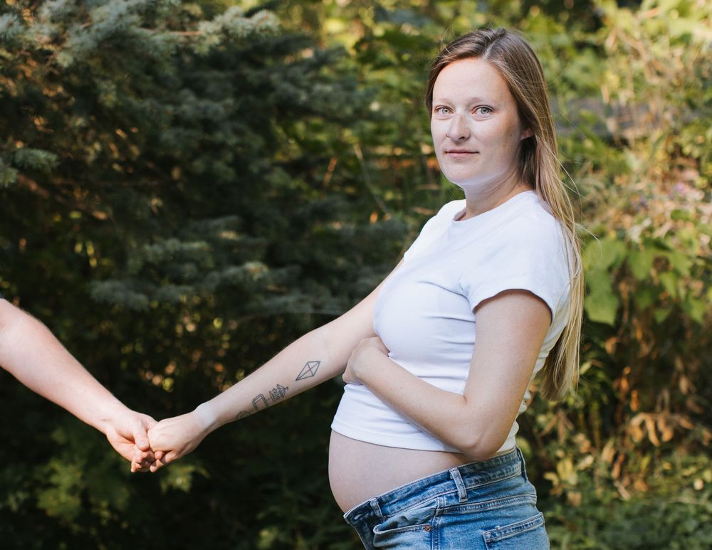 Hannah holding husband's hand during lifestyle maternity session in Flint, Michigan