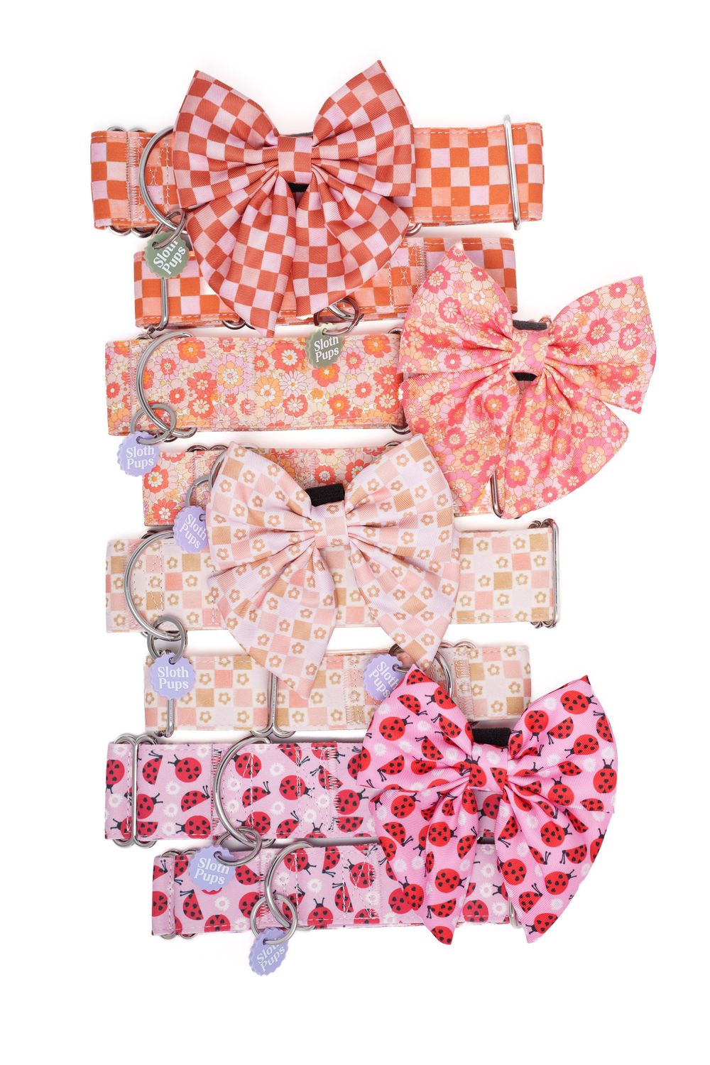 Stack of pink and orange patterned dog collars with matching bow ties, featuring checkered, floral, and ladybug prints.