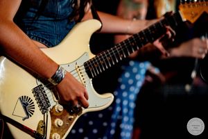 Close-up of musician playing white Fender Stratocaster electric guitar live on stage.