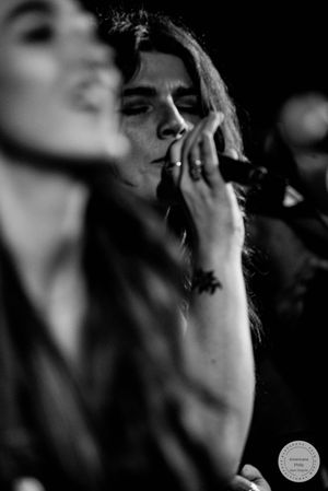 Black and white photo of female singer performing live, holding microphone close to face.