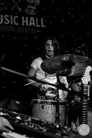 Black and white photo of a drummer performing on stage at Spring City Music Hall, playing cymbals with intensity.
