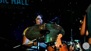 Female drummer playing cymbals on stage at Music Hall Spring City live concert.