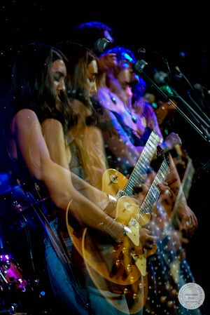 Creative multiple exposure photo of female guitarist performing live on stage.