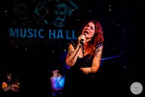 Tattooed female rock singer performing on stage at Music Hall Spring City venue.