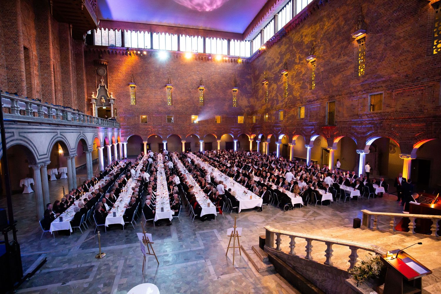 Elegant banquet hall with long white-clothed tables filled with guests at Stockholm City Hall.