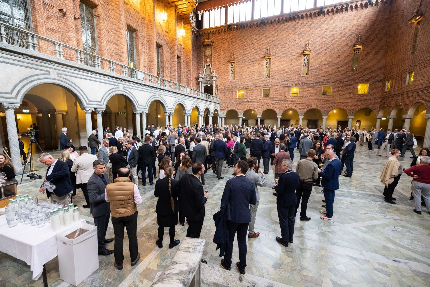 Elegant indoor reception with well-dressed guests mingling on the marble floor  at Stockholm City Hall.