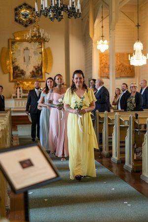 Brudtärnor på väg ut ur Järbo kyrka under en bröllopsfotografering
