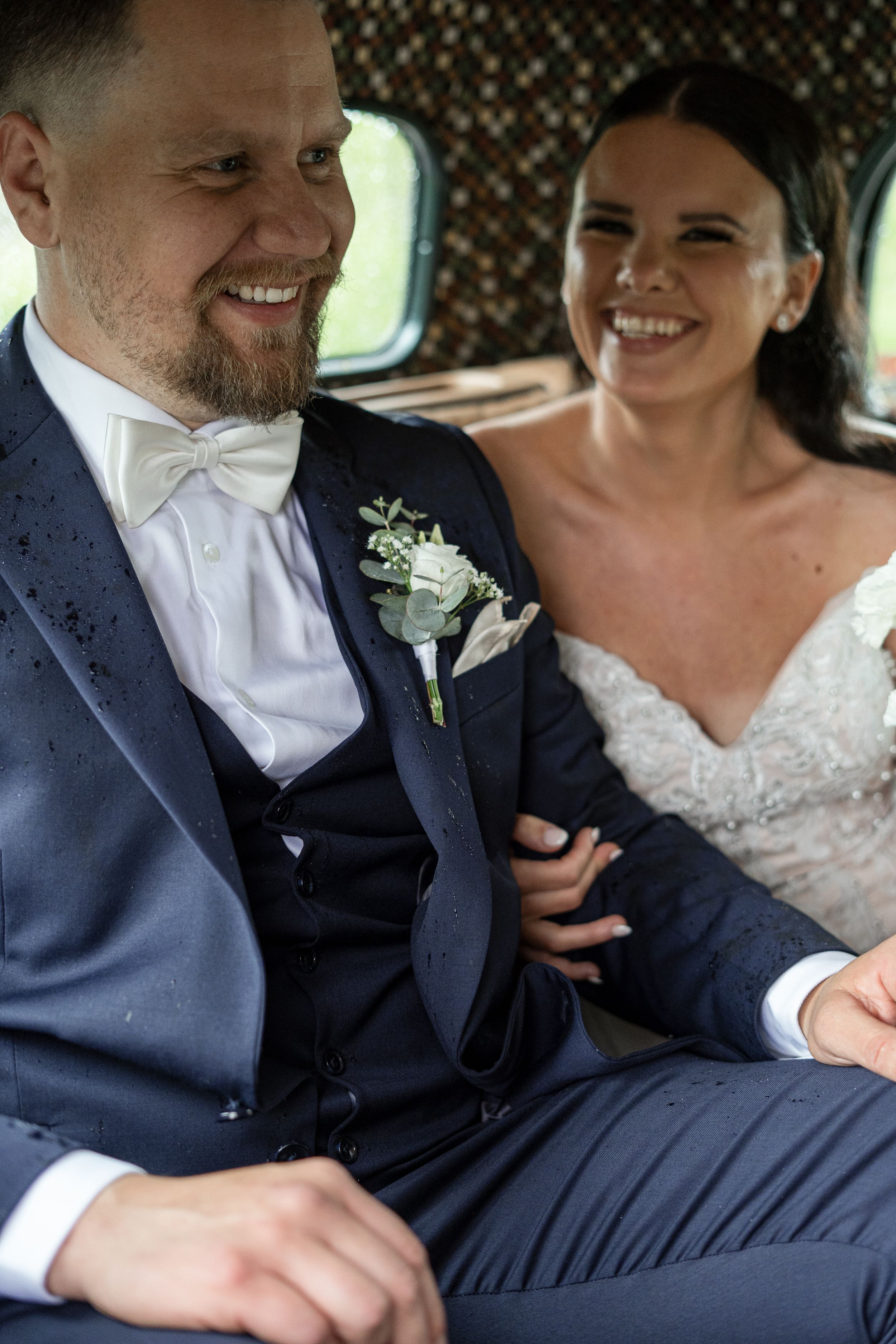 Brudpar sitter tillsammans och skrattar under sin bröllopsfotografering i Järbo, Sandviken