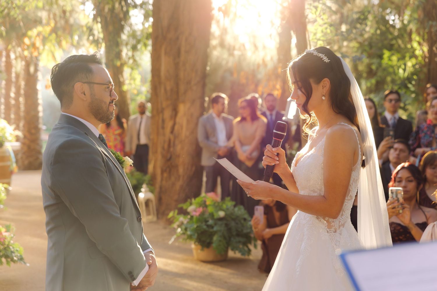 Bride reading wedding vows to groom during romantic outdoor woodland ceremony.