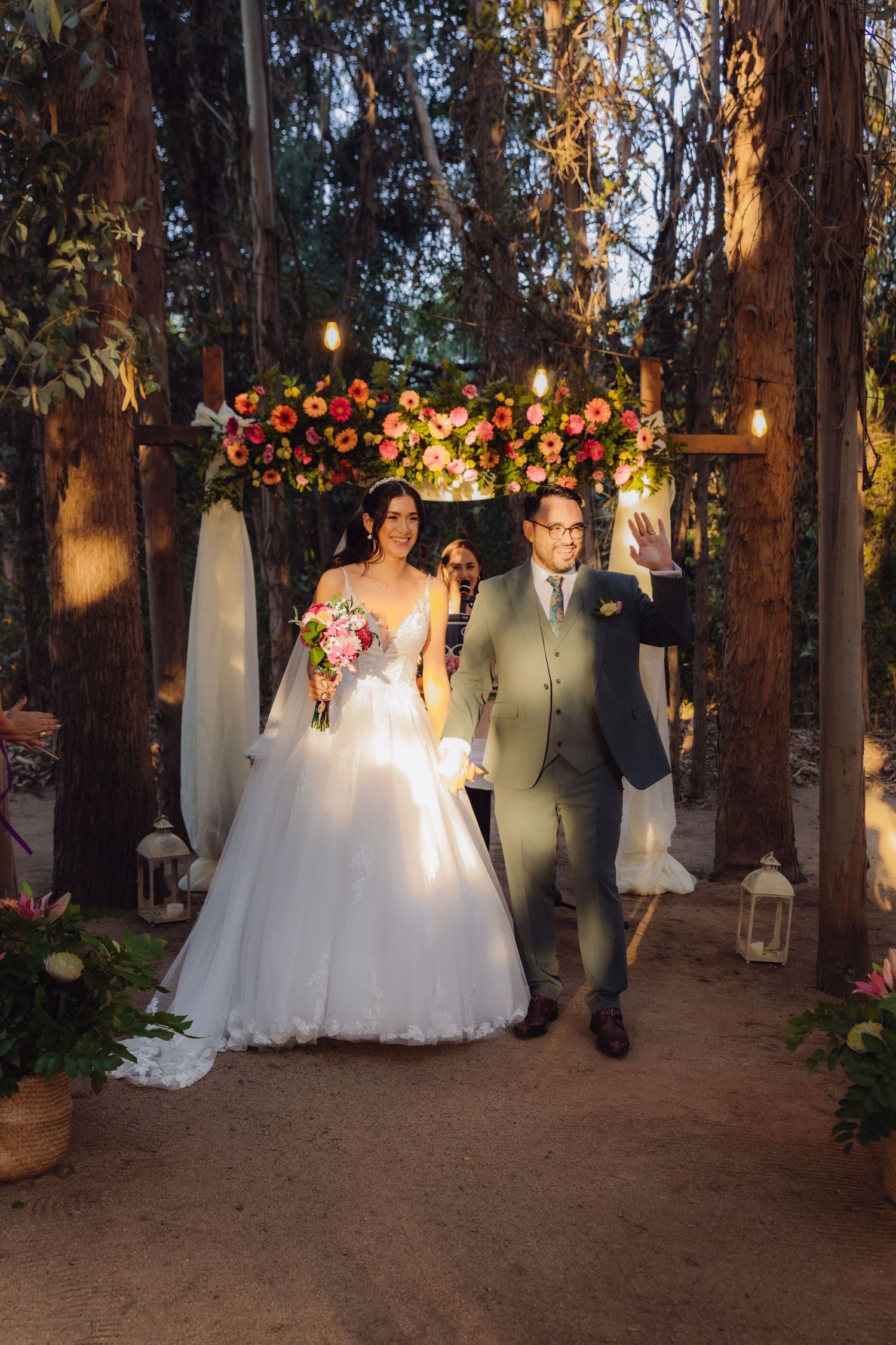 Bride and groom walking down aisle after ceremony in beautiful tree-lined outdoor wedding venue.