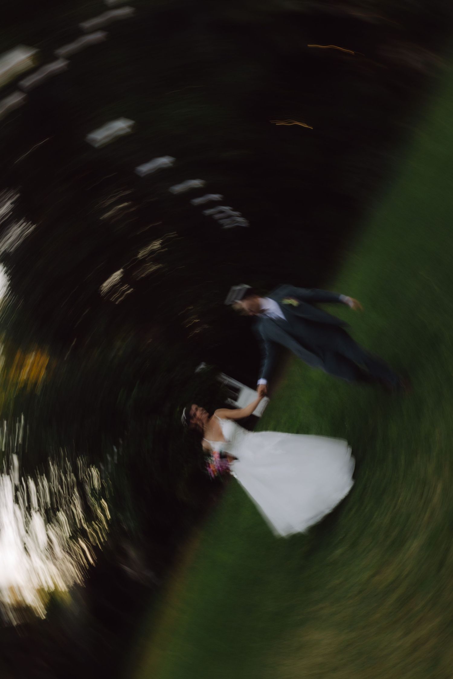 Artistic spinning motion blur photo of bride and groom dancing at outdoor wedding ceremony.