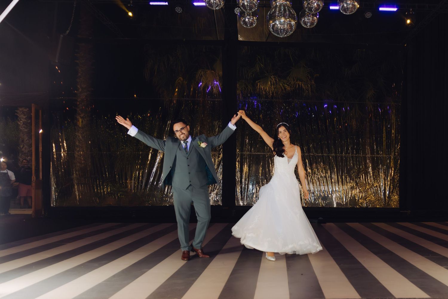 Bride and groom celebrate their first dance on a striped floor at an elegant wedding reception.
