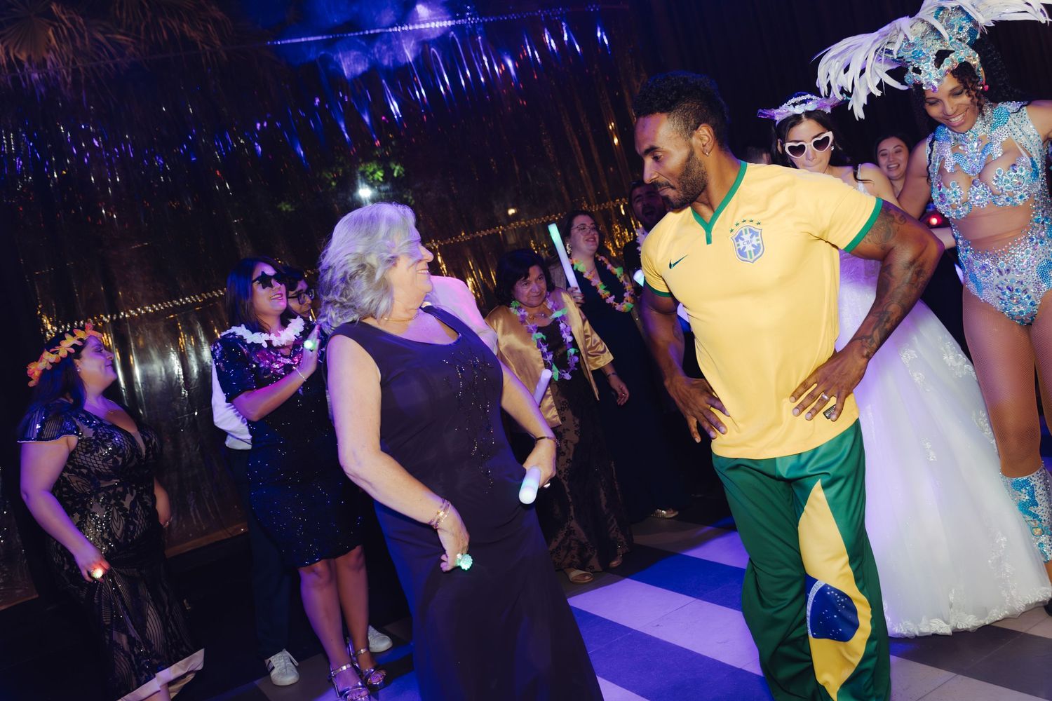 Woman in black dress dancing with man in Brazil jersey at festive wedding celebration.