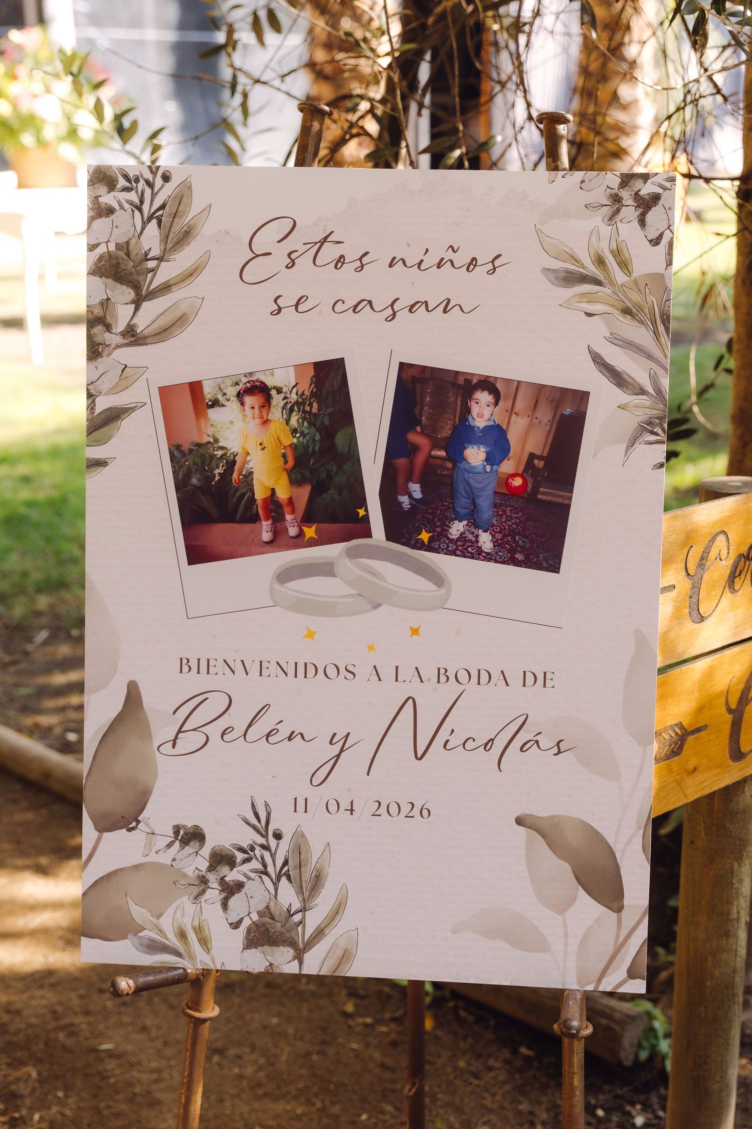 Wedding welcome sign for Belen y Nicolas dated 11-04-2026 with childhood photos and floral design.