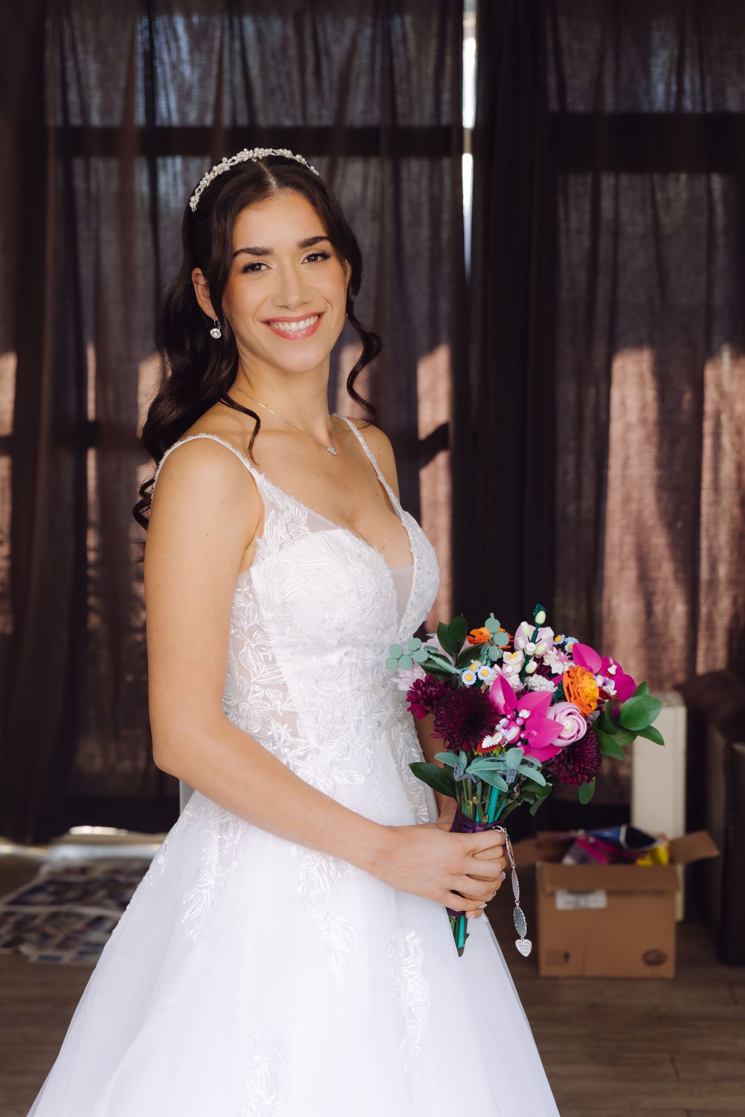 Beautiful bride in white ball gown with crystal tiara holding vibrant pink and purple floral bouquet.