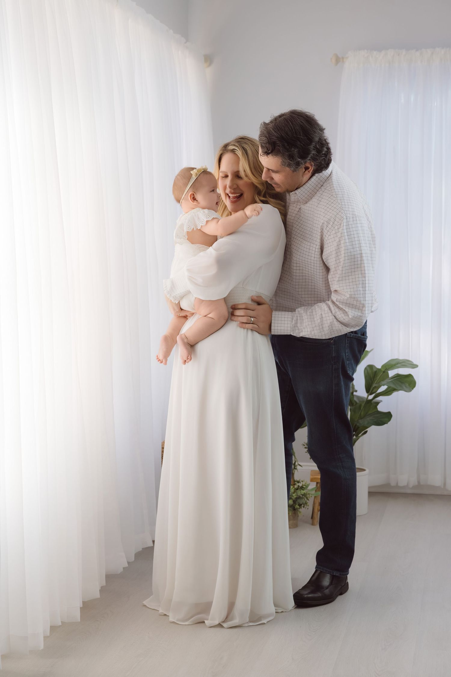 Parents holding their baby in a bright white studio