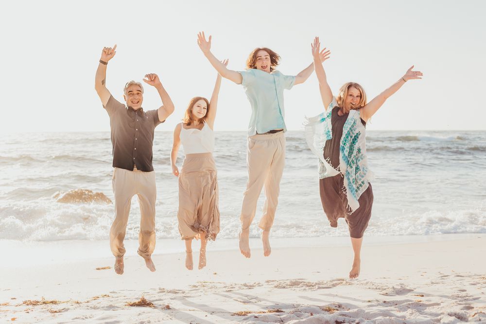 A family of four jumping in the air for a photo at the beach in Pebble Beach