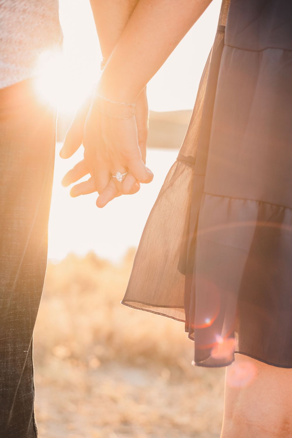 A newly-engaged couple holding hands in the sunlight