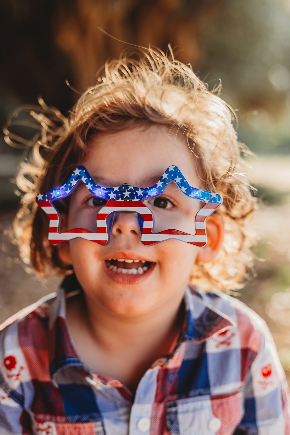 Young boy posing for a picture wearing 4th of July glasses