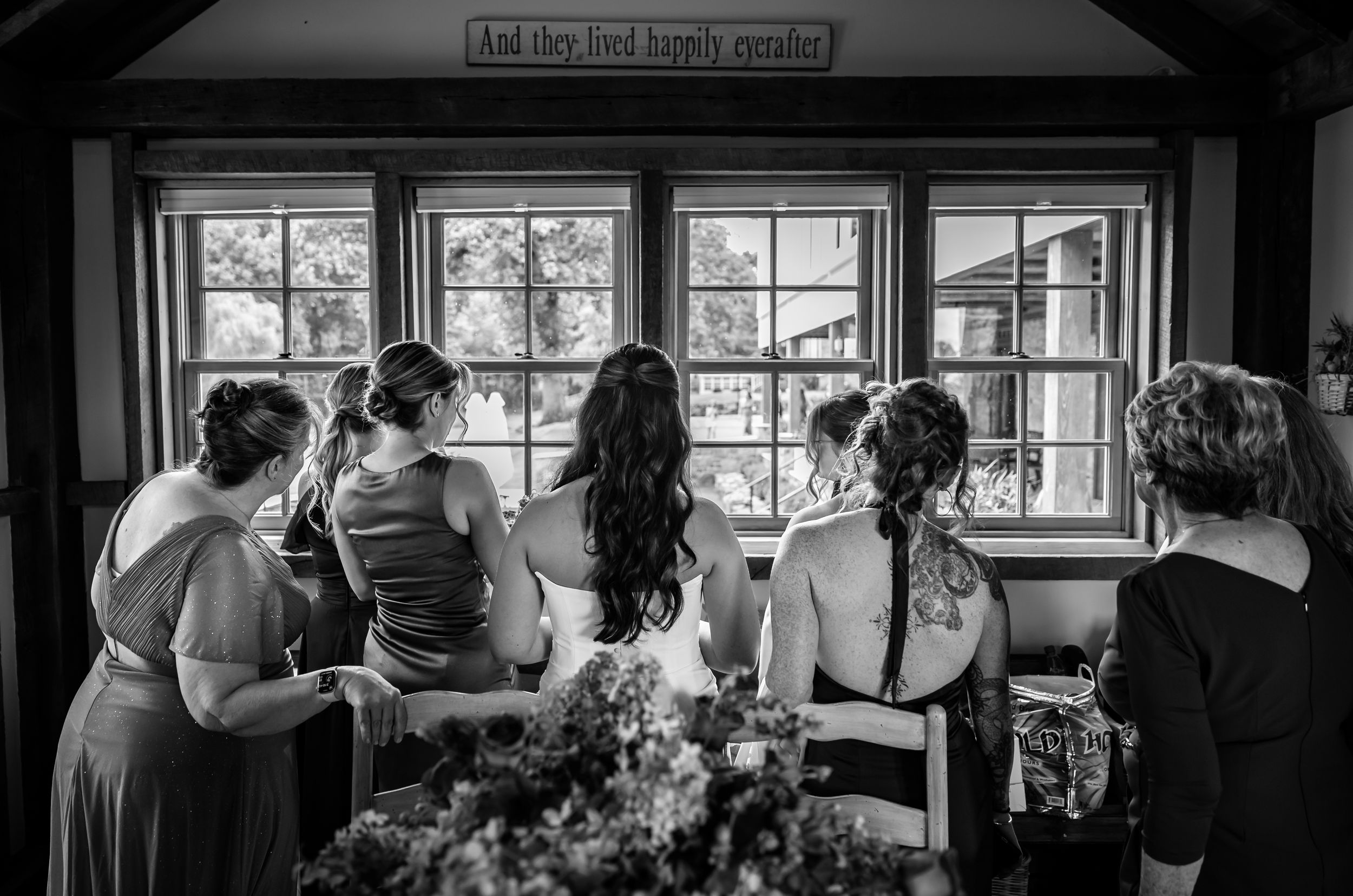 Bridal party gazing out windows beneath and they lived happily ever after sign.
