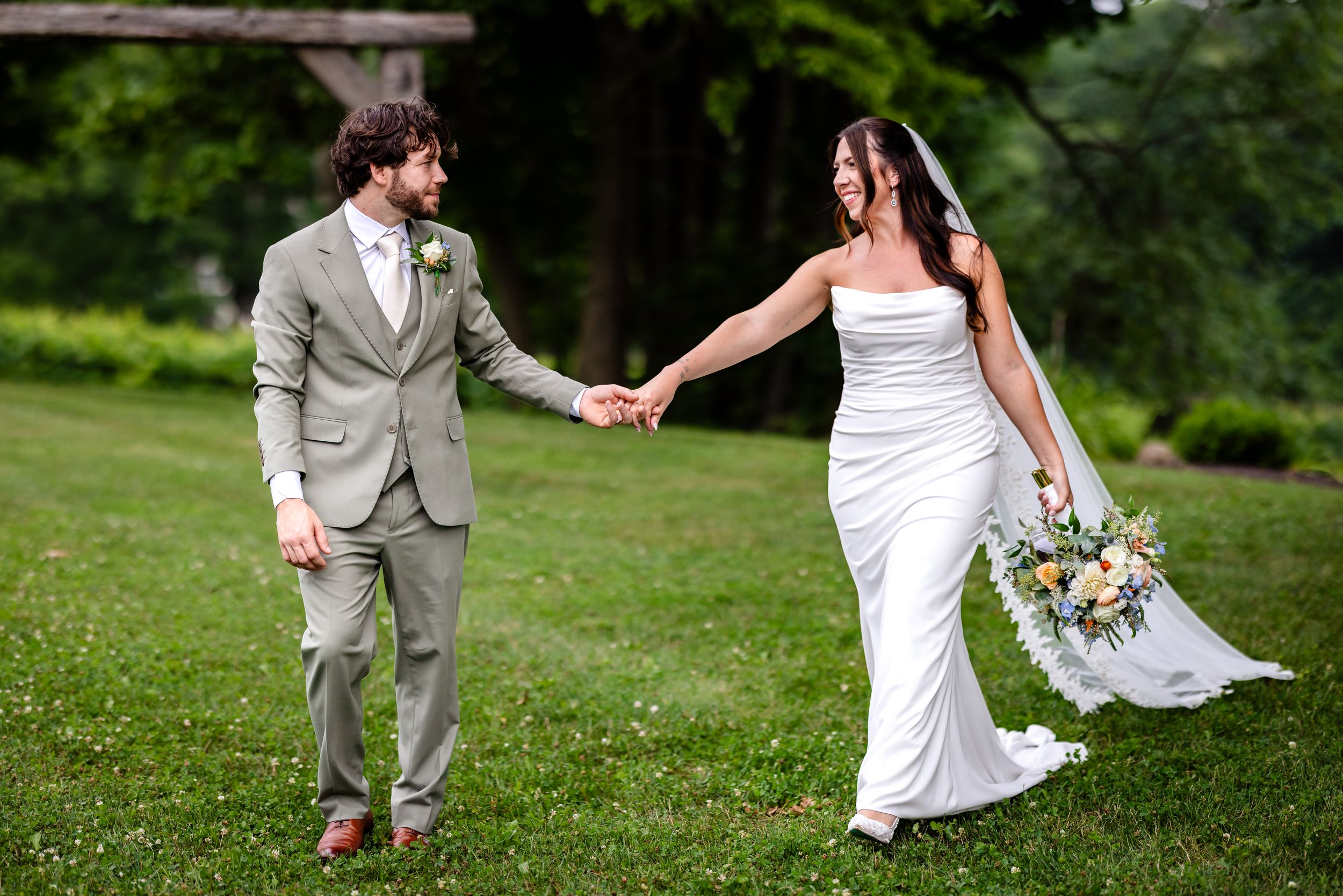 Bride and groom holding hands walking through lush green garden on their wedding day.