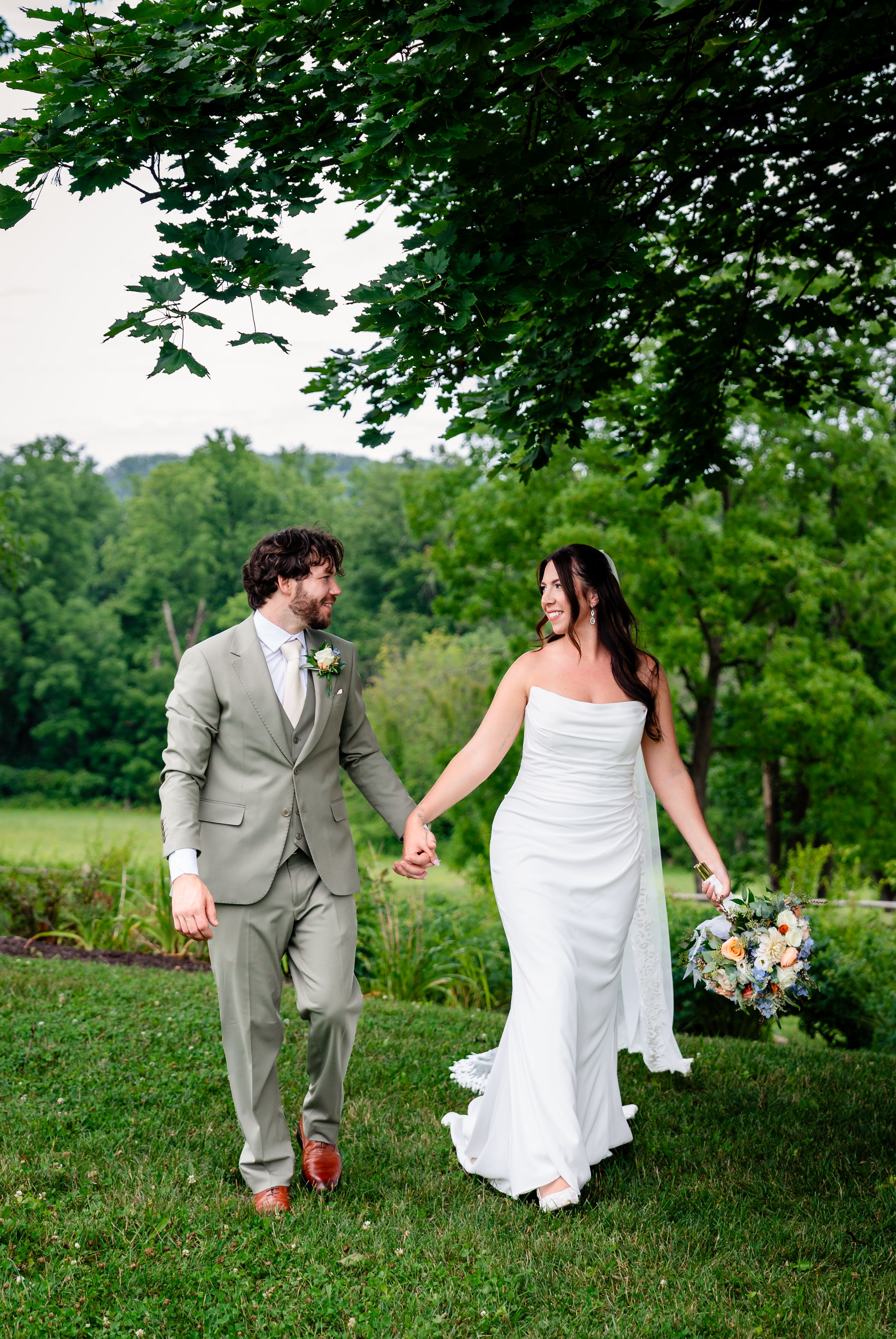 Bride and groom holding hands walking through lush green garden on their wedding day.