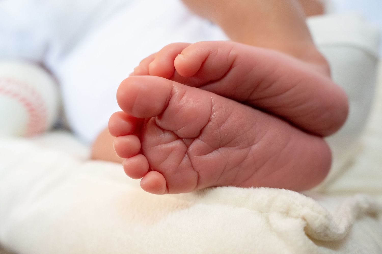 Close-up of newborn baby feet resting on a soft white blanket.