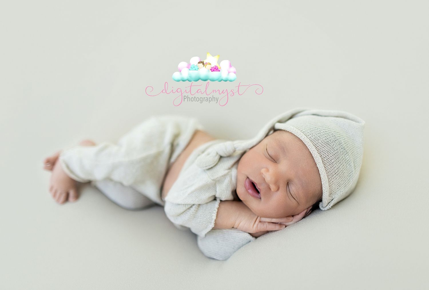 Peaceful newborn baby sleeping in a white outfit and hat on a soft neutral background in a professional photo.