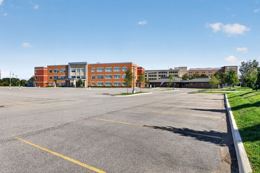 Empty parking lot in front of a modern brick office building complex on a clear sunny day.
